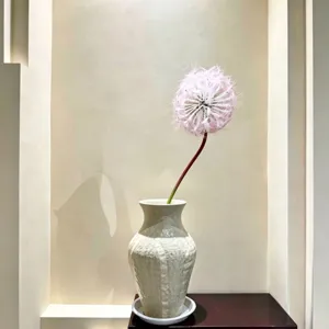 Close-up detail of artificial pink dandelion flower in ceramic vase for home decor interior style.