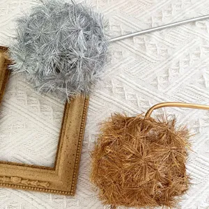 Detail shot of artificial dandelion flower arrangement, silver and gold home decor floral props.