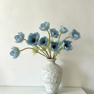 Artificial blue anemone flower bouquet in textured ceramic vase for home decor table.