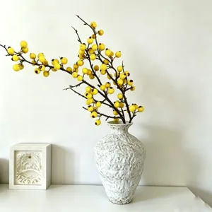Artificial yellow berry branches in textured white ceramic vase home decor arrangement