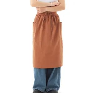 Dettaglio del grembiule corto in cotone marrone con tasche e coulisse per cucina e forno.