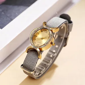 Vista detallada del reloj de cuarzo para mujer con caja ovalada dorada y correa de nailon gris.