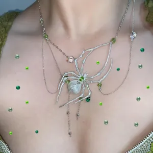 Detailed view of fairy style green gemstone stickers and unique spider necklace for body makeup.