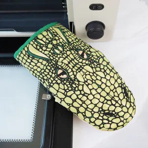 Close-up detail of green crocodile pattern heat-resistant oven mitt for kitchen baking.