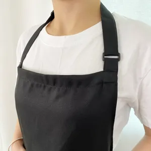 Close-up detail of a black work apron with adjustable neck strap, clean fabric texture.