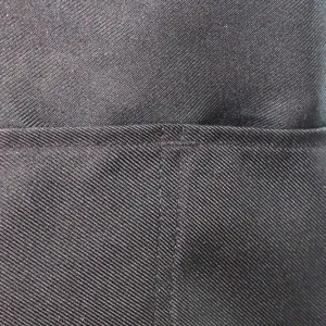 Dettaglio del tessuto del grembiule nero spesso con cuciture rinforzate e trama impermeabile.
