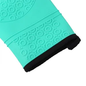 Primo piano di un guanto da forno in silicone verde acqua con motivo antiscivolo e bordo nero.
