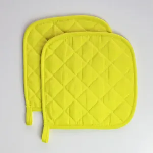 Gros plan détaillé de maniques matelassées jaune vif montrant des coutures soignées et du tissu doux.