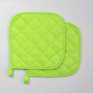 Détail de manique carrée matelassée vert vif, coussin thermique en tissu de cuisine.