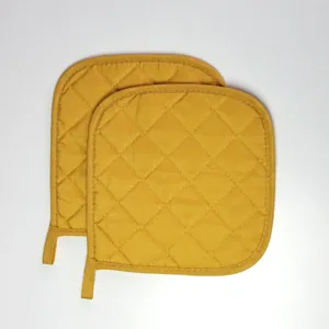 Gros plan sur le dessous de plat matelassé jaune, accessoire de cuisine résistant avec boucle.