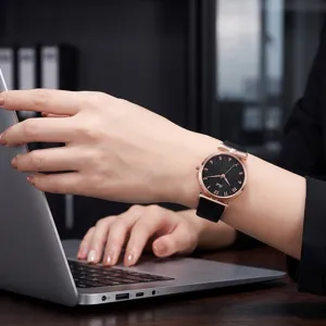 Primo piano di un orologio da donna con quadrante nero, cassa oro rosa e fiocco.