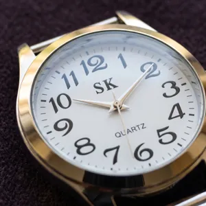 Close-up detail shot of a quartz watch with clear white dial and large black Arabic numerals.