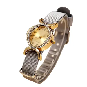 Elegante reloj de cuarzo para mujer con bisel ovalado dorado de pedrería y correa de nailon.
