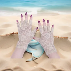 Close-up detail of women's beige lace half-finger sun protection gloves on sand.
