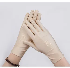Close-up of elegant champagne sun protection gloves with delicate embroidered floral details.