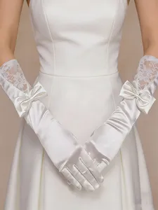 Close-up detail view of white satin wedding gloves featuring elegant lace and bow accents.