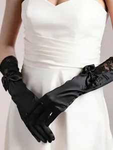 Detailed view of elegant black satin and lace bridal long gloves with cute bow decoration.