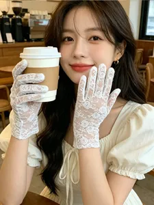 Close-up view of elegant white lace gloves featuring delicate floral patterns worn by model.