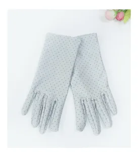 Detail view of grey polka dot spandex sun protection gloves with open fingers for driving.