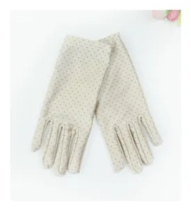 Detail view of women short polka dot gloves, elegant beige fabric with black spots.