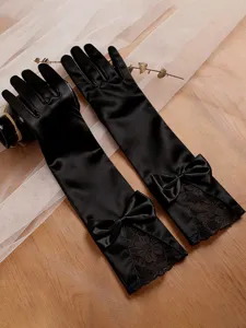 Detailed view of elegant black long satin gloves with bow and lace trim for formal wear.