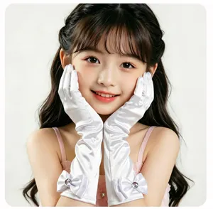 Gros plan de gants longs blancs en satin pour enfants avec un joli nœud et strass pour fêtes.