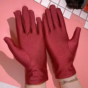 Dettaglio di guanti elastici rossi lucidi da donna, tessuto in spandex liscio, elegante accessorio.