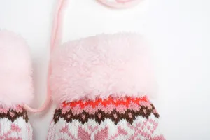 Detailansicht von rosa flauschigen Bündchen Kinder Strickhandschuhen mit Kordel.