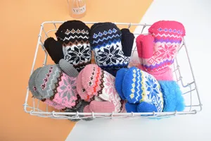 Nahaufnahme gemütlicher Kinder Winter warme Strickfäustlinge mit niedlichen Schneeflocken im Korb.