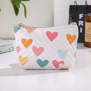 Close-up view of a cute white leather coin pouch featuring colorful heart prints and zipper.