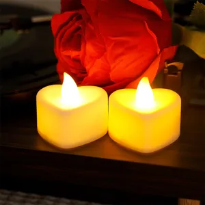 Detail view of romantic heart-shaped LED tea candles with warm ambient glow on wooden surface.