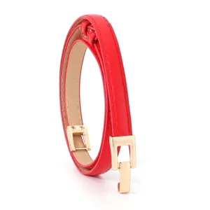 Red thin leather belt for women with elegant gold buckle, delicate detail shot for dresses.
