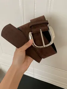 Detailed view of a wide brown suede belt featuring a large polished metallic pin buckle.