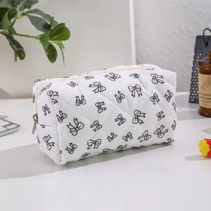 Quilted cosmetic bag with cute black bow pattern, portable zipper makeup pouch for travel storage.