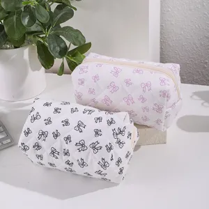 Detailed view of quilted cosmetic bags with cute bow patterns, perfect for travel storage.