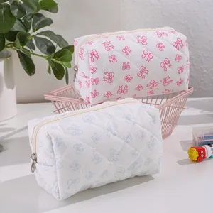 Detailed close-up of quilted cosmetic pouch featuring cute bow pattern and dual zippers.
