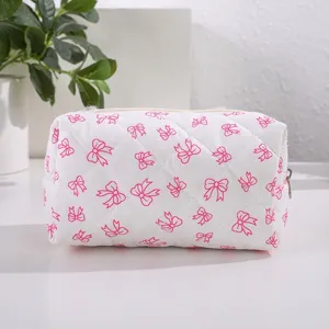 Pink quilted cosmetic bag with cute bow pattern, portable storage pouch for makeup.