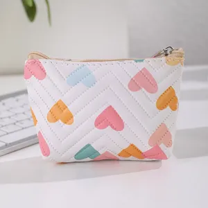 Detailed view of the white leather coin purse showcasing cute colorful heart prints and smooth zipper.