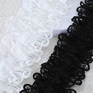 Détail de bordure en dentelle avec des motifs floraux ajourés en noir et blanc.