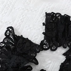 Gros-plan sur la bordure en dentelle noire, design ajoure floral exquis pour robe elegante.