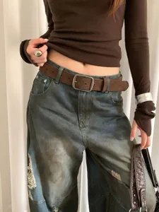 Close-up detail of retro brown suede belt with matte metal buckle, stylish accessory view.