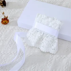 Détail de ceinture corset en dentelle blanche avec bordure ajourée et ruban satin.