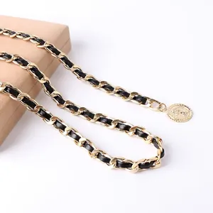 Detailed view of the luxury black leather intertwined gold chain belt with coin pendant.
