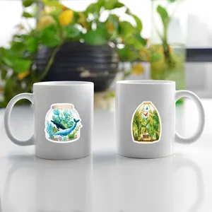 Detail view of two white ceramic mugs featuring beautiful watercolor bottle world illustrations.