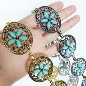 Detalle en primer plano de cadena de cintura metal turquesa boho con diseño floral.