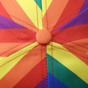 Detail du haut de casquette de baseball rayée arc-en-ciel, tissu multicolore et coutures rouges.