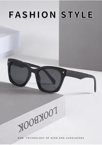 Close-up detail of stylish black square sunglasses with dark lenses and subtle gold accents.