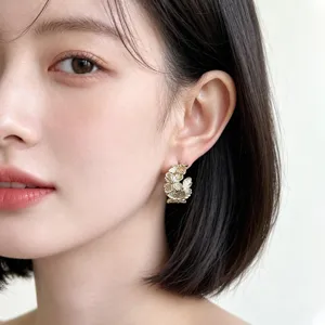 Close-up view of elegant gold floral textured hoop earrings worn by model, fine detail.