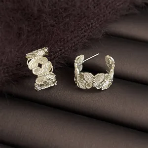 Detailed view of elegant golden butterfly hoop earrings, luxury commuting style jewelry.