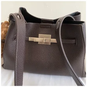 Detail view of a brown leather shoulder bag with metallic lock closure and dual straps.